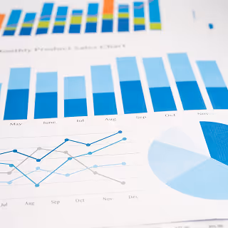A close-up view of printed financial documents displaying bar graphs, pie charts, and line graphs in various shades of blue.