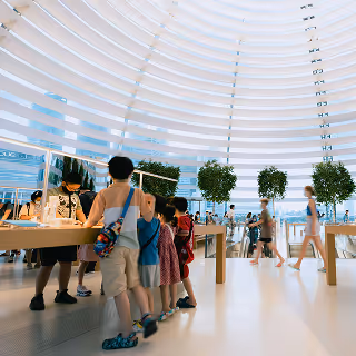 Interior of a sleek, brightly lit store featuring modern architecture, lush plants, and visitors interacting with product displays, reflecting innovative customer experiences.