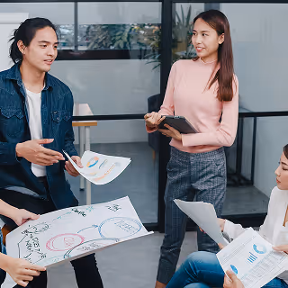 Young professionals gathered in a modern office, discussing charts and reports, actively engaging with each other.