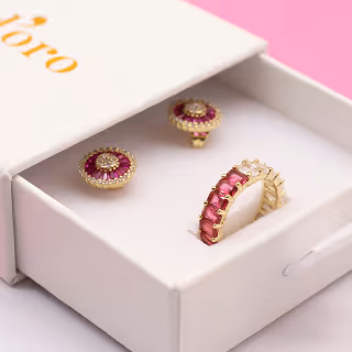 Delicate earrings and a ring presented in a branded jewelry box, showcasing craftsmanship and elegance.