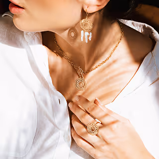 Woman elegantly adorned with matching gold necklace, earrings, and ring, capturing sophistication and style.