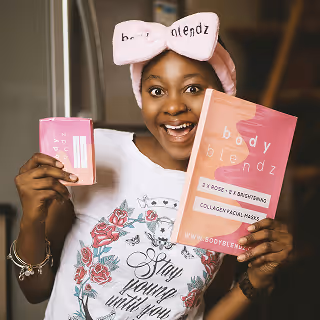 Smiling young woman in pajamas holding a pink box and matching flyer for 'body blendz' skincare products, wearing a branded headband and radiating excitement.