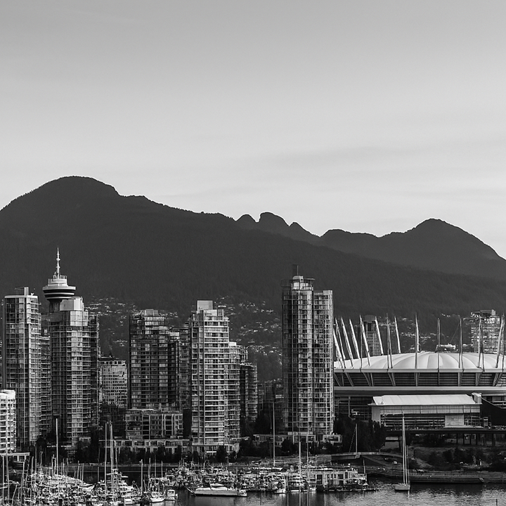 A black-and-white view of Vancouver’s skyline with high-rise buildings, BC Place Stadium, and the North Shore mountains in the background.