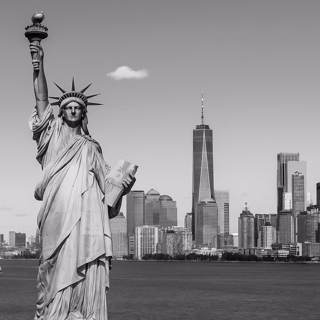Black-and-white view of the Statue of Liberty in the foreground with One World Trade Center and Manhattan skyline in the background.