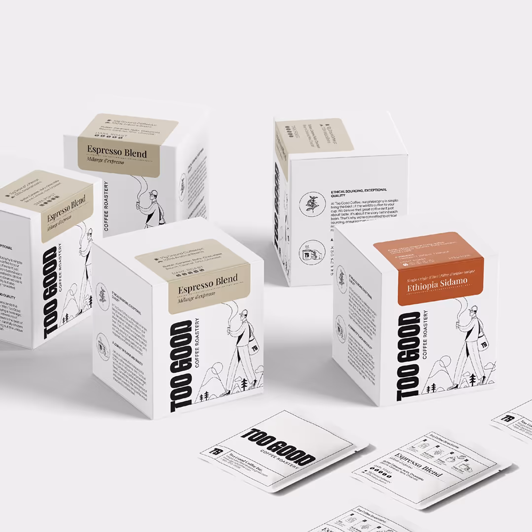 Minimalist packaging for Too Good Coffee Roastery, featuring white boxes with illustrated graphics and labels for espresso and Ethiopia Sidamo blends.