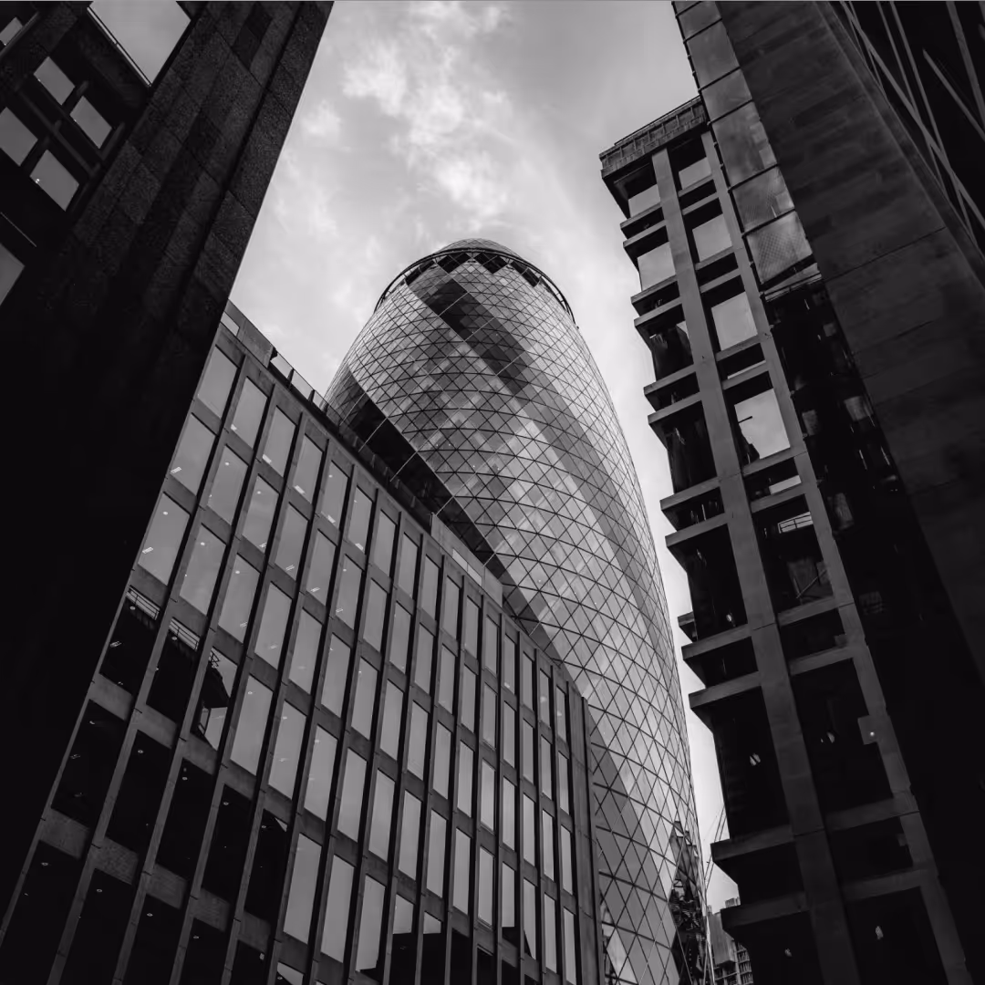 Iconic bullet-shaped skyscraper framed by surrounding office buildings, shot from street level in black and white.