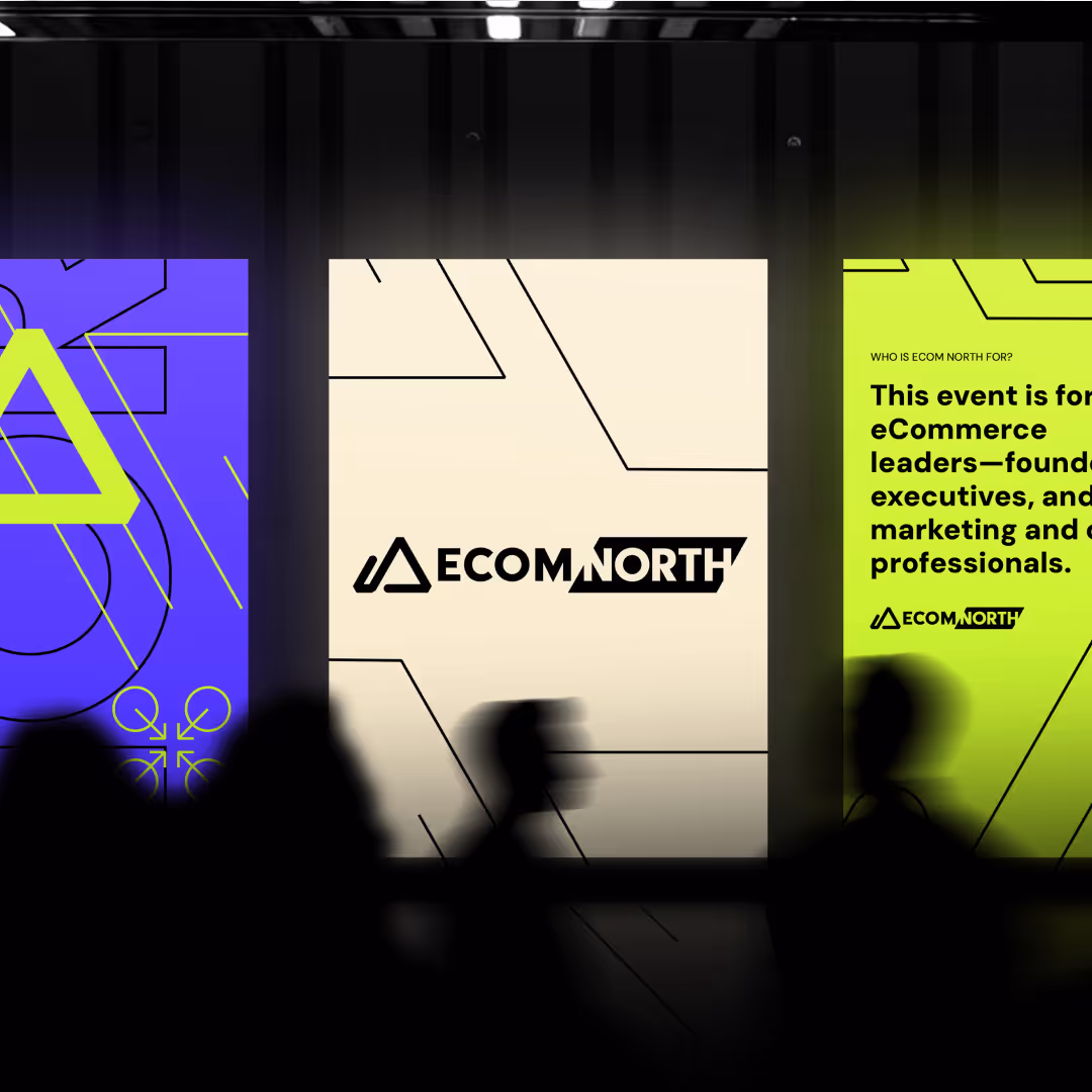 Another view of ECOM North event displays with bold neon green, purple, and cream panels featuring geometric branding and event information.