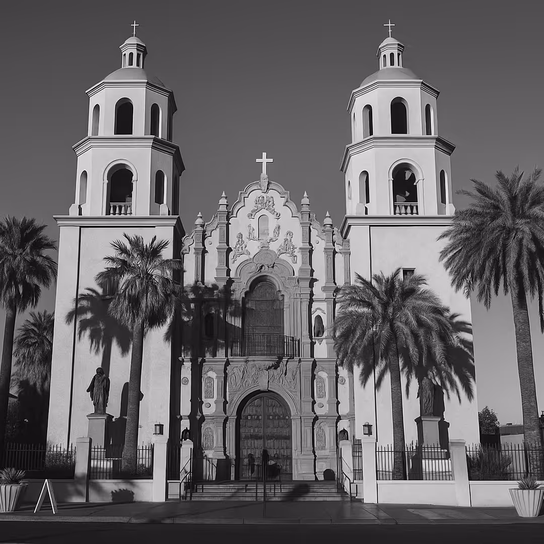 A black-and-white photo of St. Augustine Cathedral in Tucson, Arizona, with twin towers, palm trees, and ornate Spanish Colonial architecture.