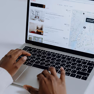 Close-up of a laptop screen displaying an Airbnb-style interface with property listings and a map, suggesting online accommodation search and booking.