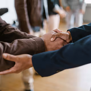 Close-up of two individuals shaking hands in a professional setting, representing trust, partnership, and client relationships in fintech.