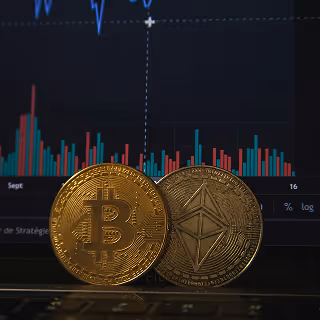 Bitcoin and Ethereum coins placed in front of a financial chart showing price fluctuations.