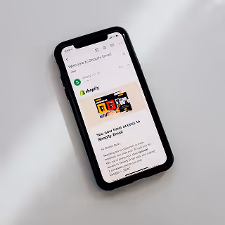Smartphone screen showing a welcome email from Shopify Email, emphasizing e-commerce platform setup and marketing.