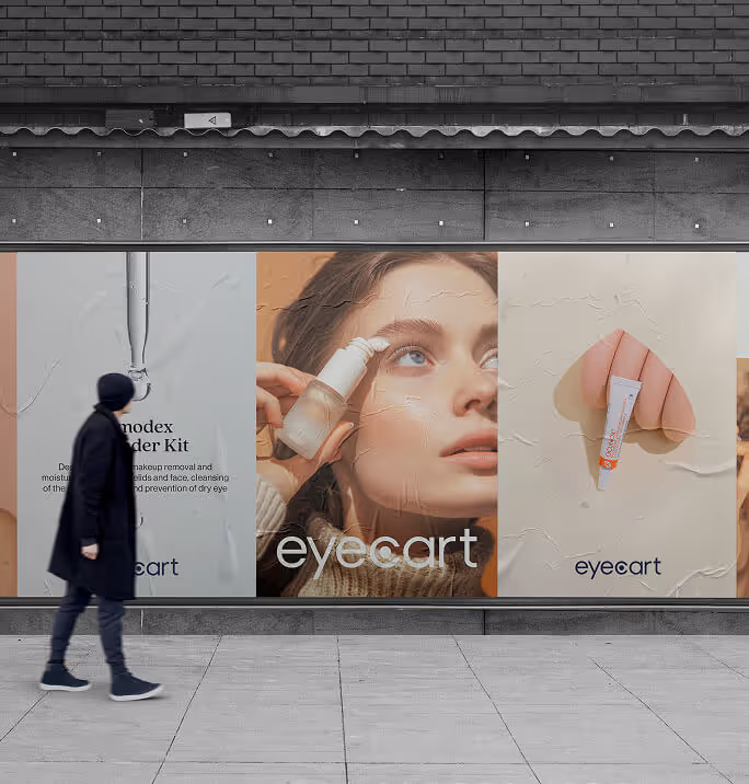 A person walks past a row of large street posters featuring Eyecart branding, product shots, and a close-up of a woman applying eye care serum.