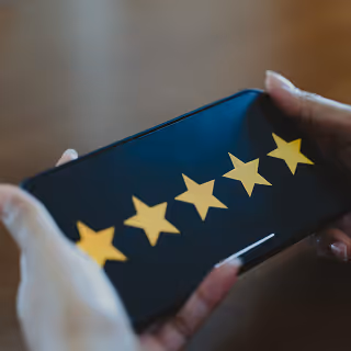Hands holding a smartphone displaying a five-star rating, symbolizing excellent customer service or product satisfaction.