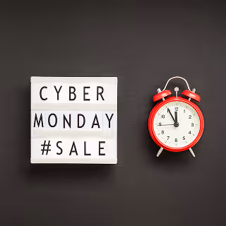 Lightbox sign reading “CYBER MONDAY #SALE” next to a red alarm clock on a dark background, emphasizing urgency and promotions.