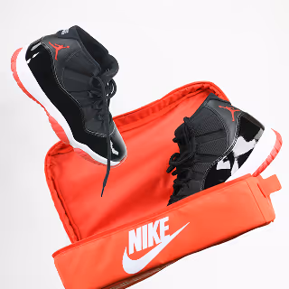 Nike Air Jordan sneakers with red case – A pair of black and red Nike Air Jordan sneakers displayed above an open red carrying case with the Nike logo, on a white background.