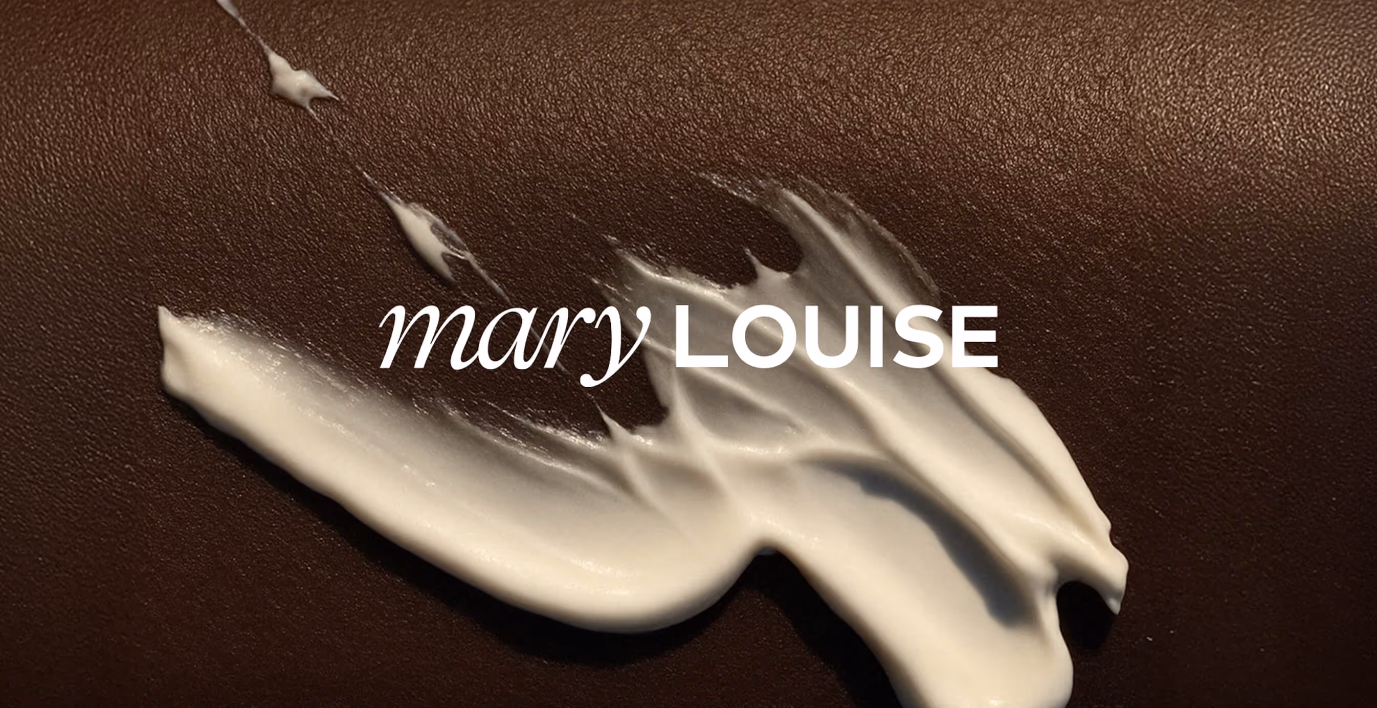 Close-up of Mary Louise logo placed over a textured brown background with a white cream smear, highlighting luxury skincare branding.