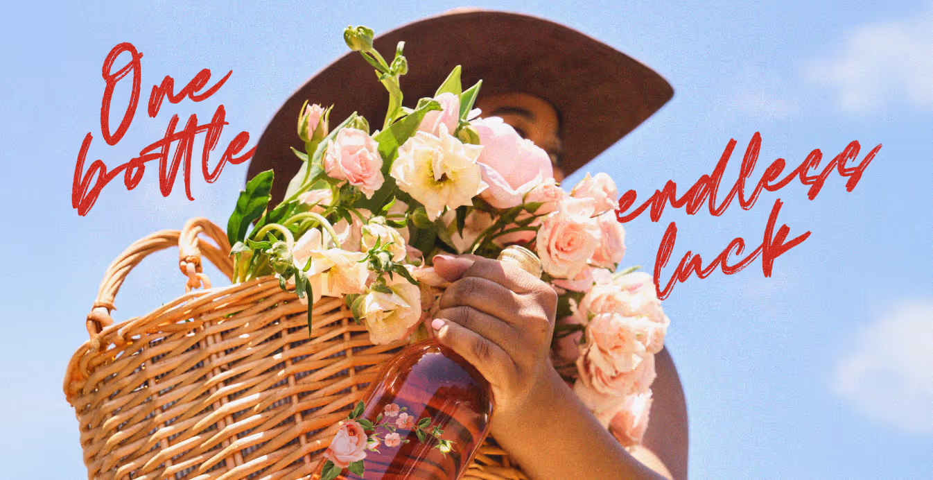 A woman in a sun hat holds a wicker basket filled with pink flowers and a Lucky Girl rosé wine bottle. Red handwritten text reads “One bottle, endless luck.”