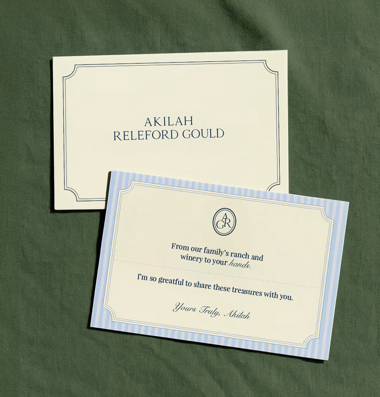 Two cards on green fabric, one reading “Akilah Releford Gould” and the other featuring a note: “From our family’s ranch and winery to your hands… Yours Truly, Akilah.”