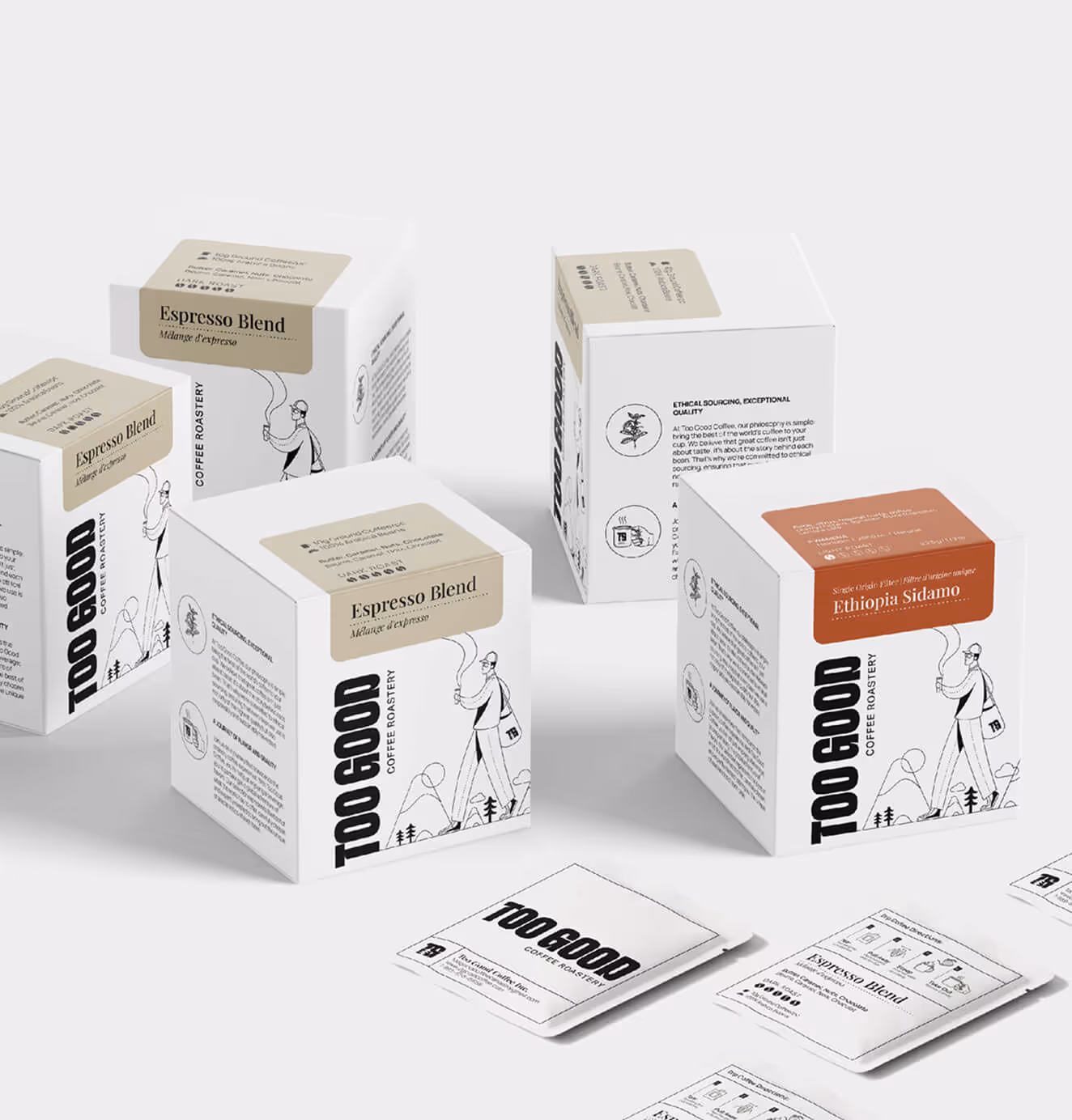 A collection of Too Good Coffee Roastery boxes, including Espresso Blend and Ethiopia Sidamo, arranged on a light surface alongside flat coffee sachets.