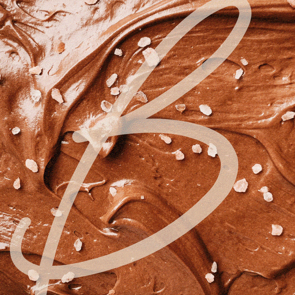 Animated background of rich chocolate swirls with sprinkled sea salt, overlaid by a large scripted “B” from the Butter Cake Shoppe logo.