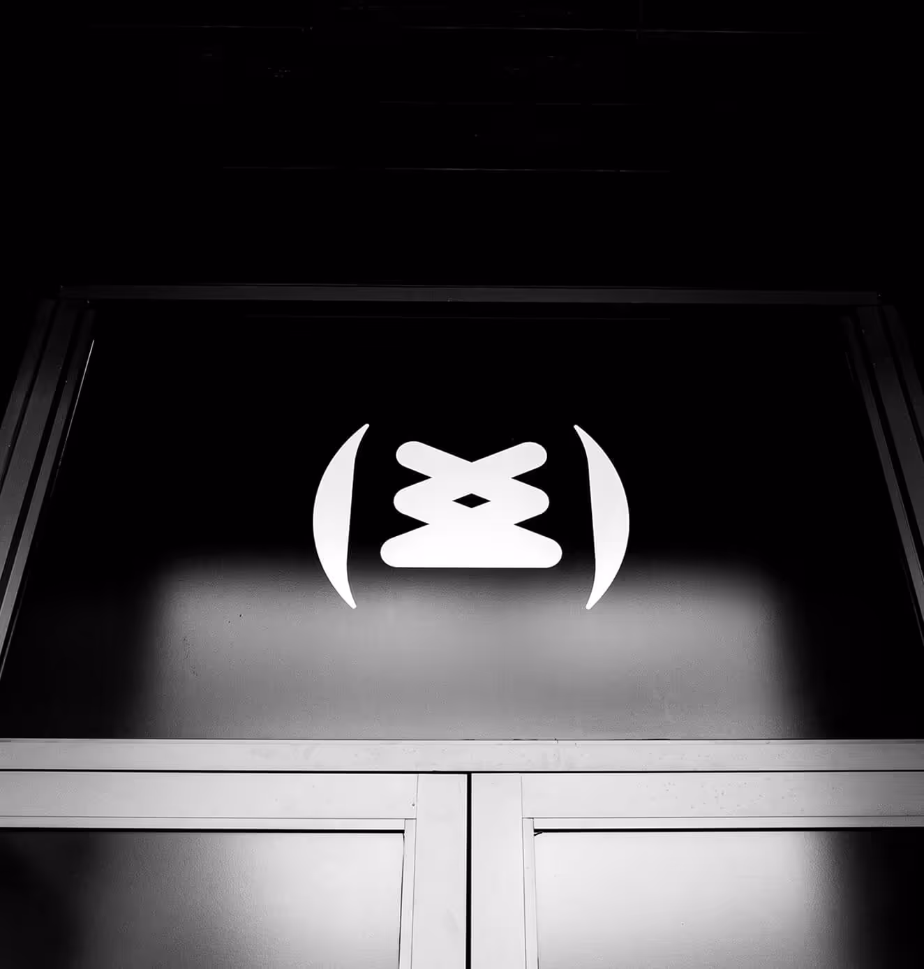 Black and white photo of the Sneakertopia logo above a storefront entrance, symbolizing sneaker culture and community.