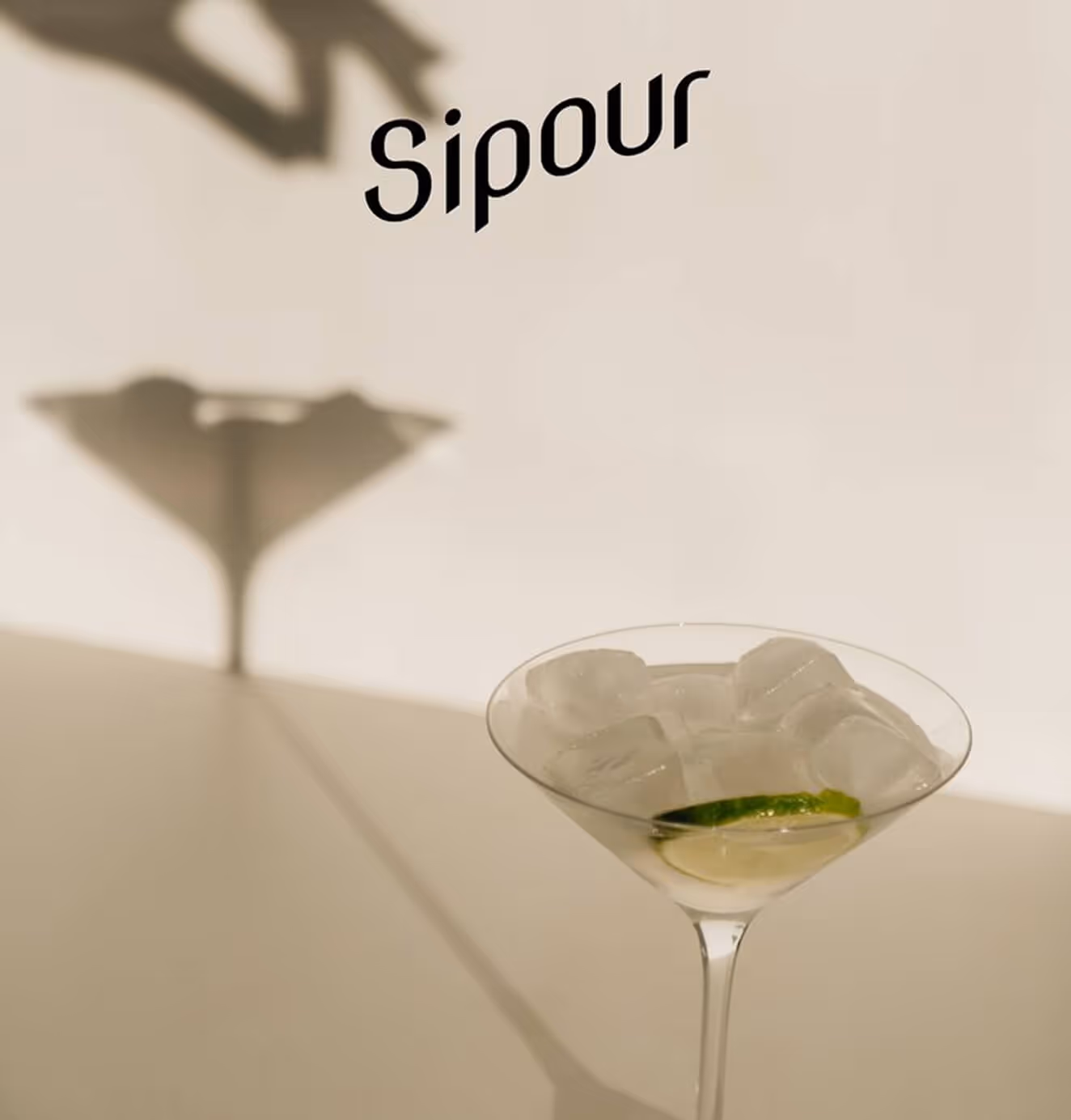 A martini glass with ice and lime casting a shadow under the Sipour wordmark, evoking brand sophistication.