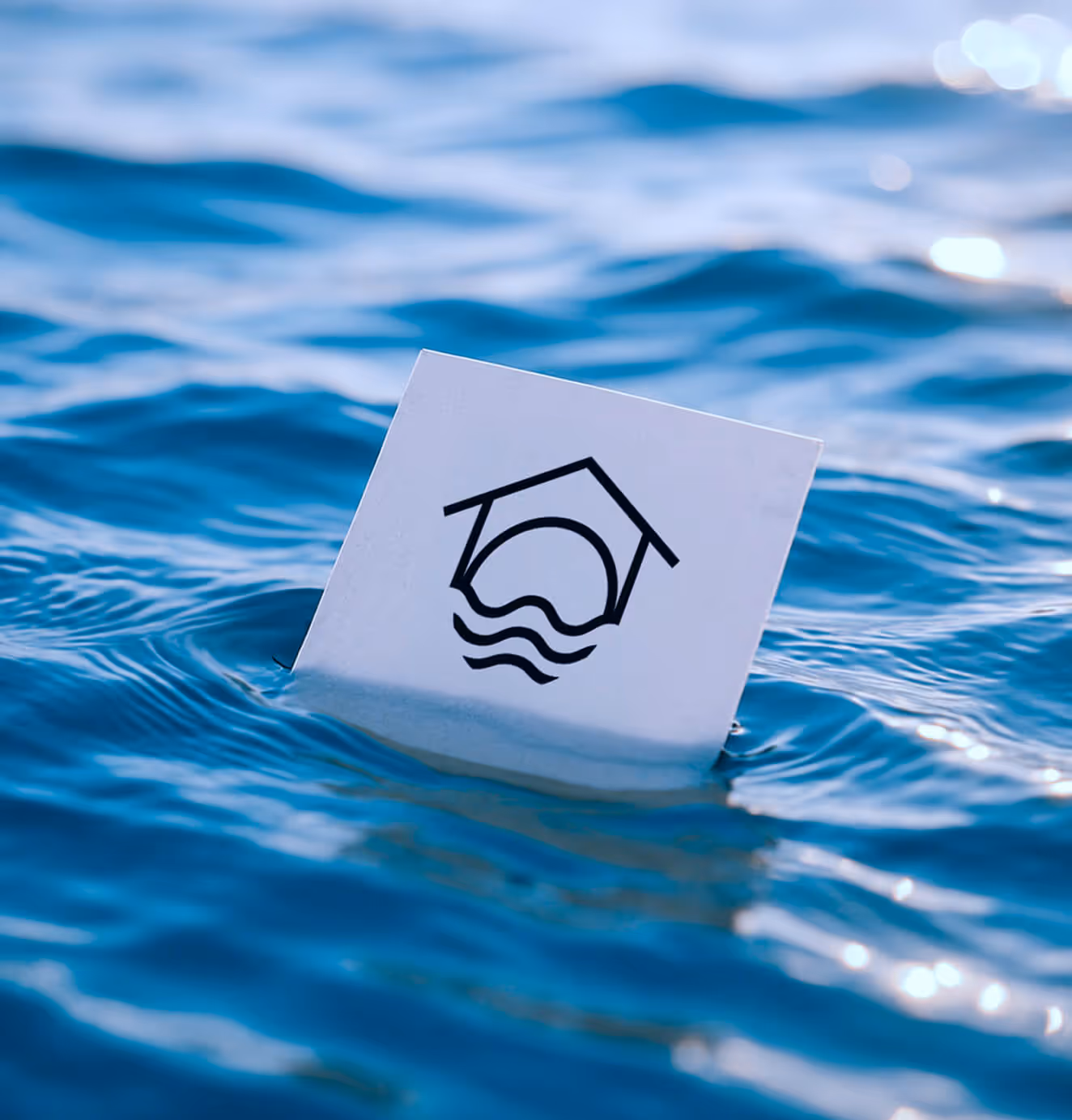 Laundry House logo card floating on blue water, symbolizing freshness, cleanliness, and the brand’s connection to purity and trust.