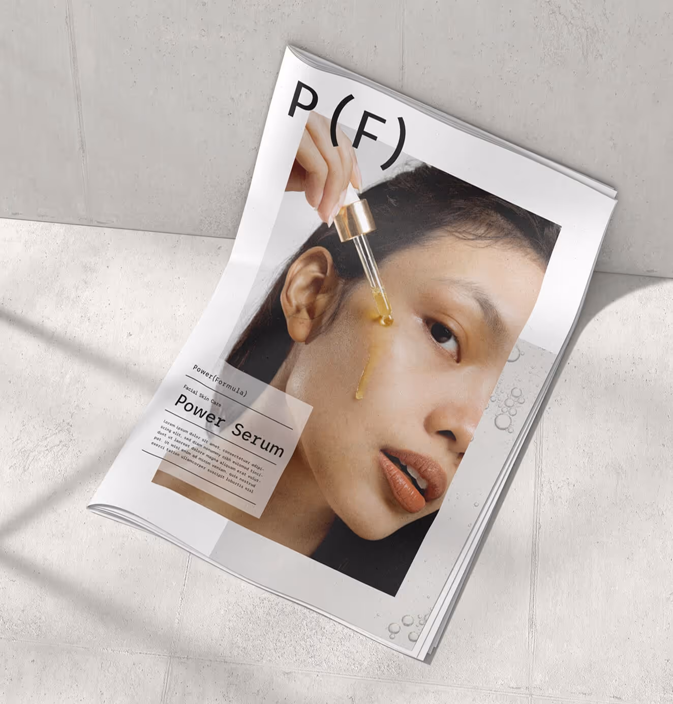 Open magazine spread featuring a model applying Power (Formula) Power Serum with a dropper, highlighting modern editorial skincare branding.