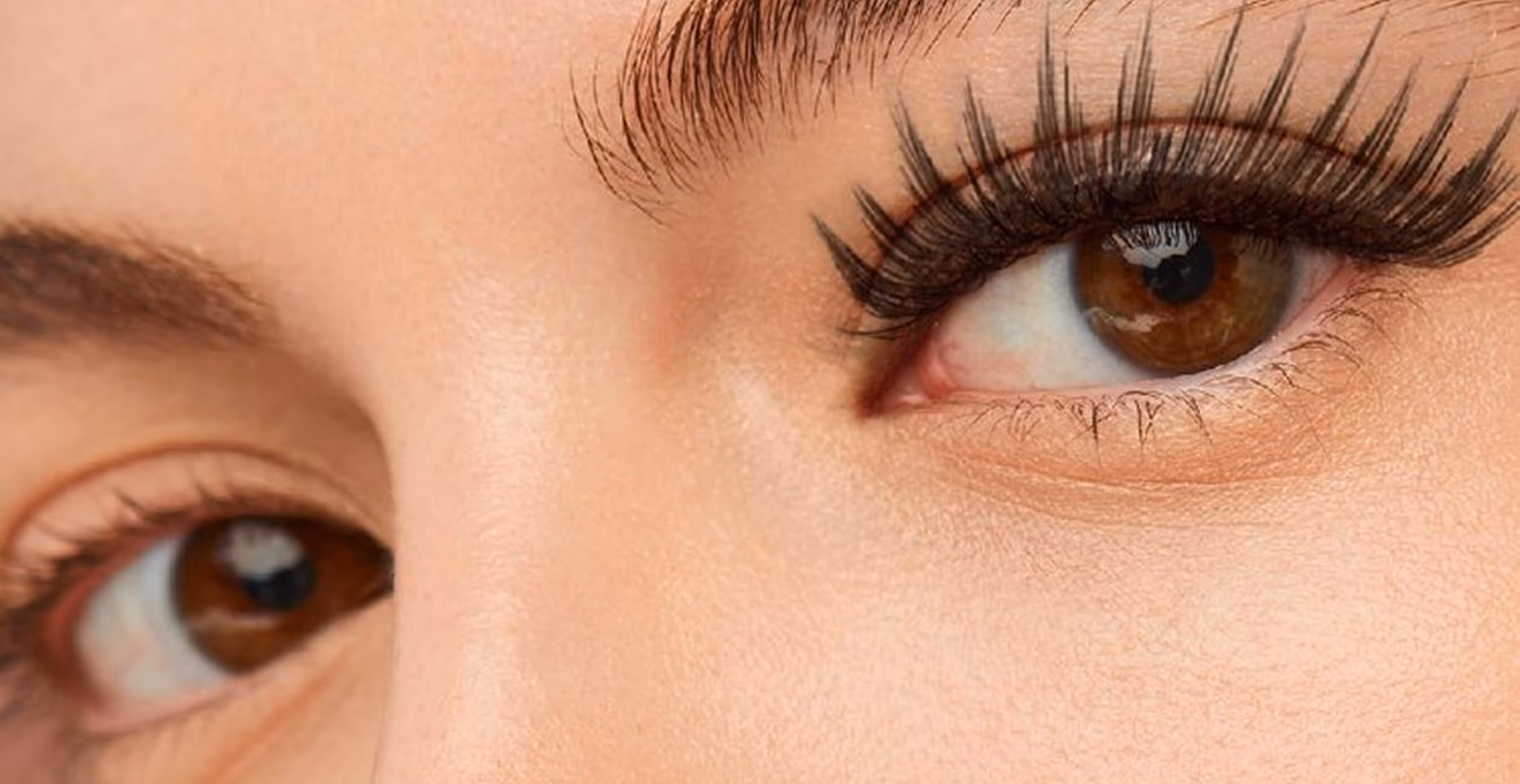 Close-up view of a woman’s brown eyes wearing natural, lightweight Pure Lashes with the brand logo in the corner.