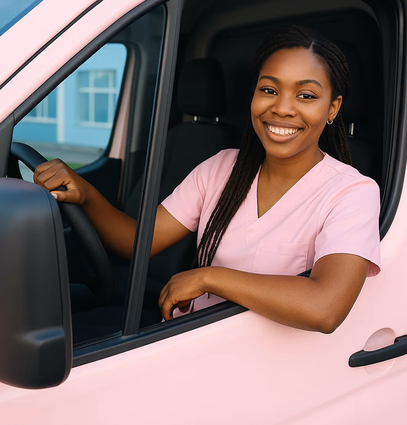 Unified driver in pink scrubs smiling from the driver’s seat of a pink transport van.