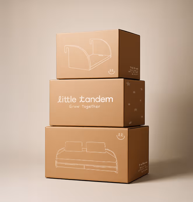 Three stacked brown shipping boxes display white illustrations of children’s furniture and the Little Tandem logo with the words “Grow Together.”