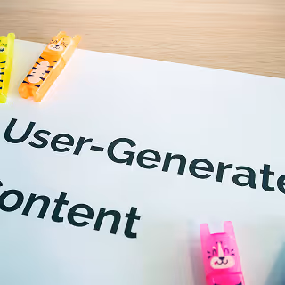 Paper labeled ‘User-Generated Content’ on a desk with colorful animal-shaped clips holding the corners.