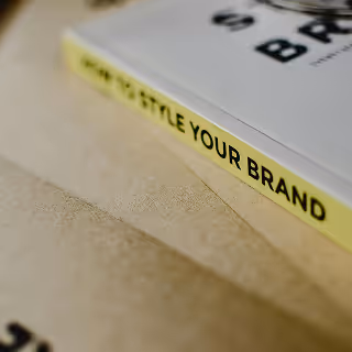 Angled close-up of a book titled "How to Style Your Brand" resting on a kraft paper surface, emphasizing branding and design.