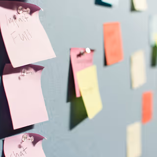 Colorful sticky notes with handwritten words pinned to a board, representing brainstorming and idea generation for brand naming.