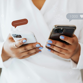 Person holding two smartphones with social media icons like likes and comments floating above, wearing a white outfit with matching blue nail polish.