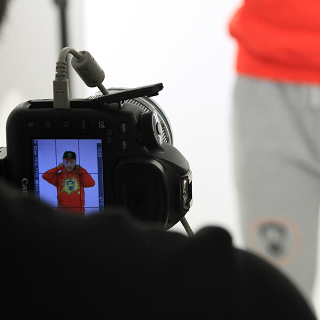 A camera capturing a model in a red hoodie during a photoshoot, illustrating brand image creation and consistency.
