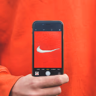 A smartphone photographing the Nike logo on a red sweatshirt, emphasizing strong brand identity and visual branding.