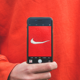 A smartphone photographing the Nike logo on a red sweatshirt, emphasizing strong brand identity and visual branding.
