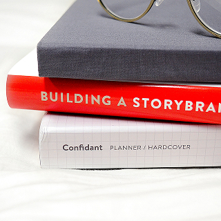 Stack of books including "Building a StoryBrand" and a planner, symbolizing the importance of brand storytelling and strategy.