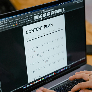 A close-up of a laptop displaying a document titled “CONTENT PLAN,” with a person’s hands typing on the keyboard.