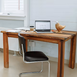 Minimalist workspace with a wooden desk, black chair, coffee cup, papers, and a laptop open to an e-commerce platform.