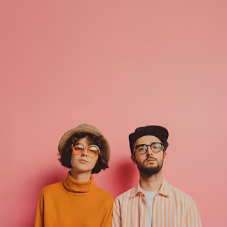 A stylish young woman and man standing against a solid pink background, both wearing sunglasses and trendy clothing, looking directly at the camera with neutral expressions.