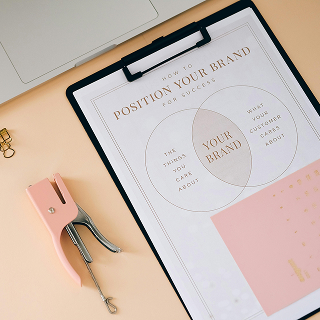A clipboard with a diagram titled “How to Position Your Brand for Success,” showing overlapping circles labeled with customer and business priorities.