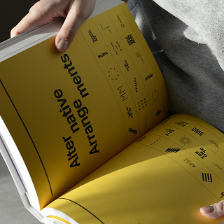 A yellow brand guideline book open to a spread showcasing “Alternative Arrangements” of logo designs, with a grid of black logo variations and text layout examples.