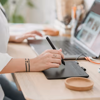 Close-up of hands typing on a laptop with brand strategy notes, charts, and coffee on the desk.