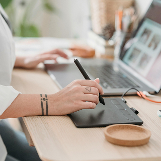 Close-up of hands typing on a laptop with brand strategy notes, charts, and coffee on the desk.