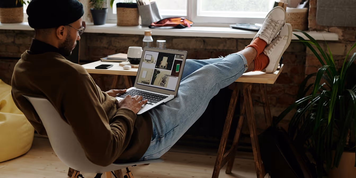 Person smiling while working on a laptop surrounded by colorful brand concept designs.
