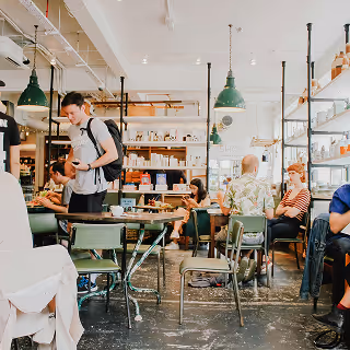 Busy café interior with people ordering, talking, and working at tables in a lively atmosphere.