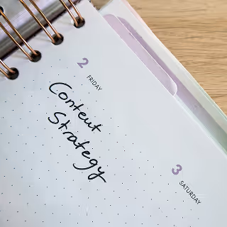 A close-up of a notebook planner showing the words “Content Strategy” handwritten on a date page.